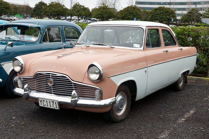 two old cars are parked in a parking lot