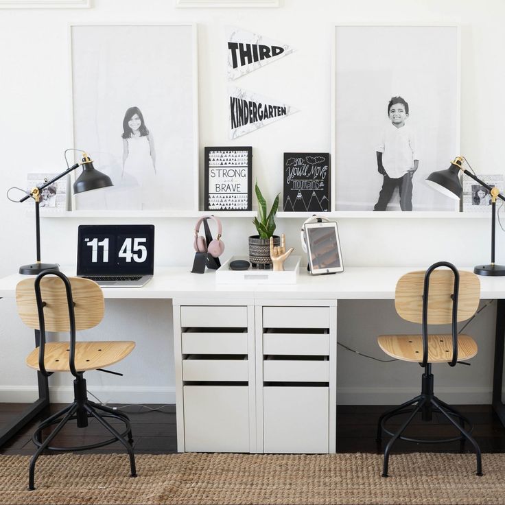 two chairs are sitting at a desk in front of pictures on the wall and below them