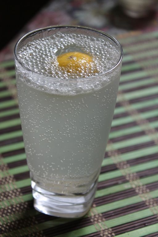 a close up of a drink on a table with water and an orange in it