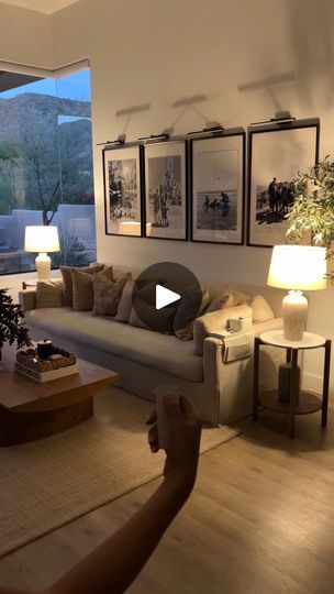 a living room filled with furniture next to a window covered in plants and framed pictures