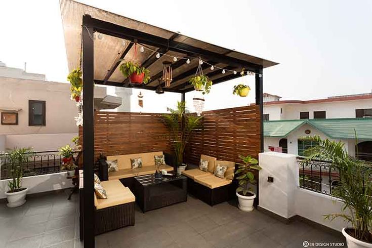 an outdoor living area with couches, tables and potted plants on the roof