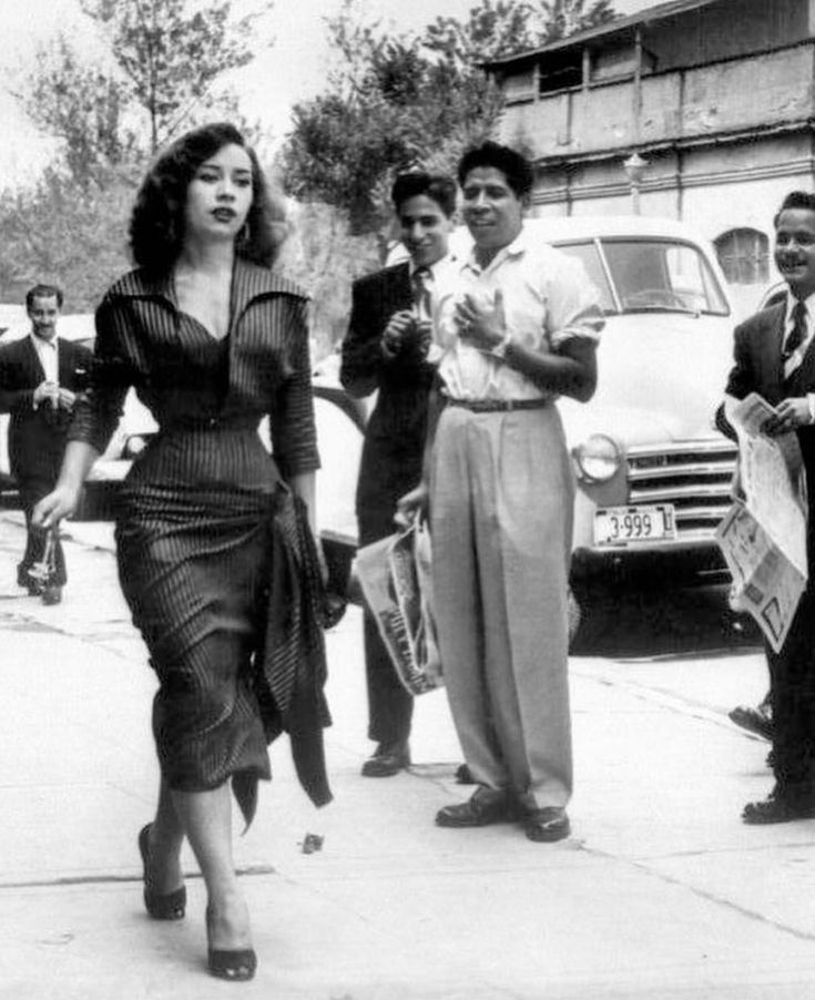 black and white photograph of woman walking down the street with other people in front of her