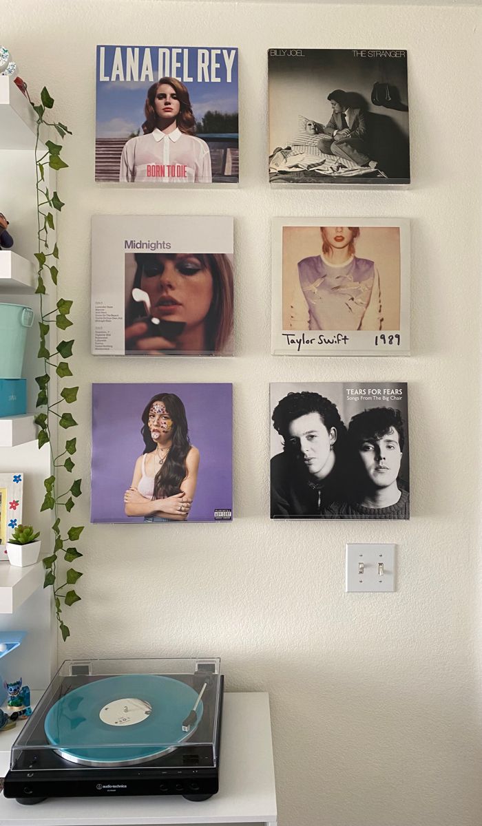 a record player sitting on top of a white table next to a wall covered in pictures