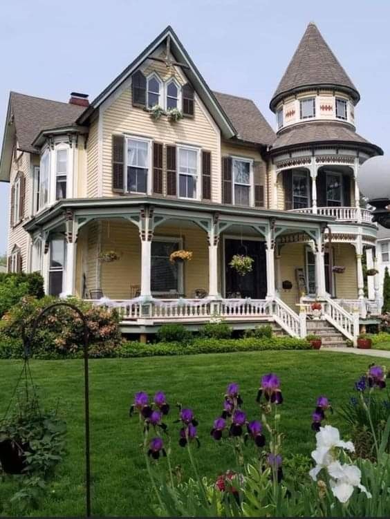 an old victorian style house with flowers in the front yard