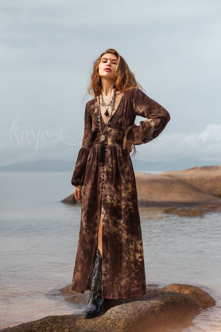 Introducing our gorgeous Brown Tie Dye Maxi Dress, a stunning combination of boho-chic and comfort. Crafted from ultra-soft organic cotton gauze, this dress offers a luxurious and gentle feel against your skin. The mesmerizing tie-dye pattern in rich brown adds a touch of uniqueness and artistry to your wardrobe. Each piece is carefully hand-dyed, creating a one-of-a-kind masterpiece that reflects the beauty of organic dyeing techniques. The long puffy sleeves evoke a sense of effortless elegance.  The elastic on the back waist ensures a super easy and comfortable fit, while enhancing your natural curves. The front of the dress is adorned with fabric-covered buttons, carefully crafted by hand for a truly distinctive touch. All of our colors are achieved through our botanical eco dye proces Ankle Boots With Dress Maxi, Luxury Cotton Long Sleeve Maxi Dress, Luxury Bohemian Festival Maxi Dress, Luxury Bohemian Fitted Maxi Dress, Luxury Designer Bohemian Dress, Rustic Bohemian Dress, Free People Maxi Dress Long Sleeve, Ankle Boots Dress Maxi, Boho Dress Maxi Bohemian