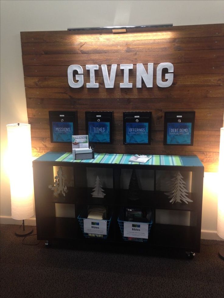 a table with several boxes on it in front of a sign that says giving and three lamps