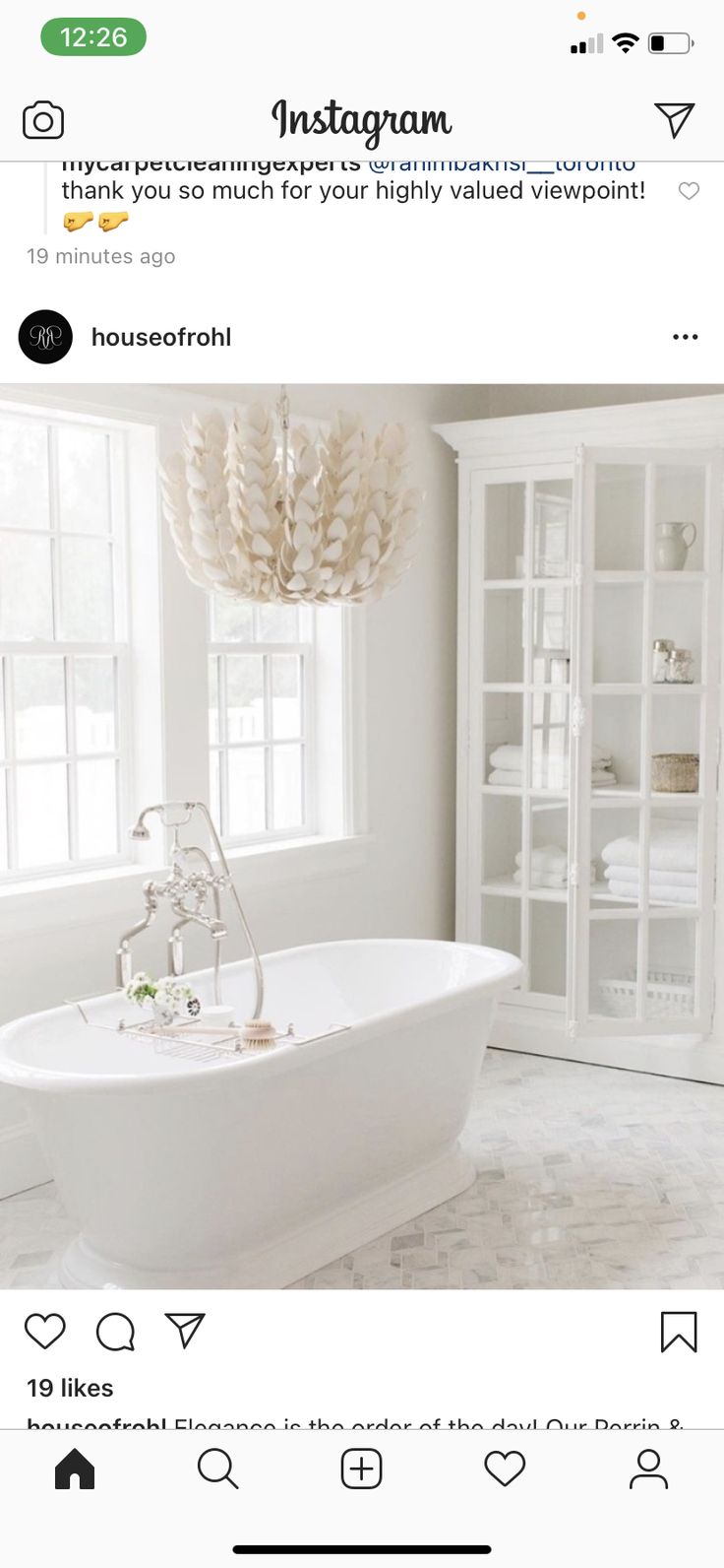 a white bath tub sitting under a window next to a book shelf with books on it