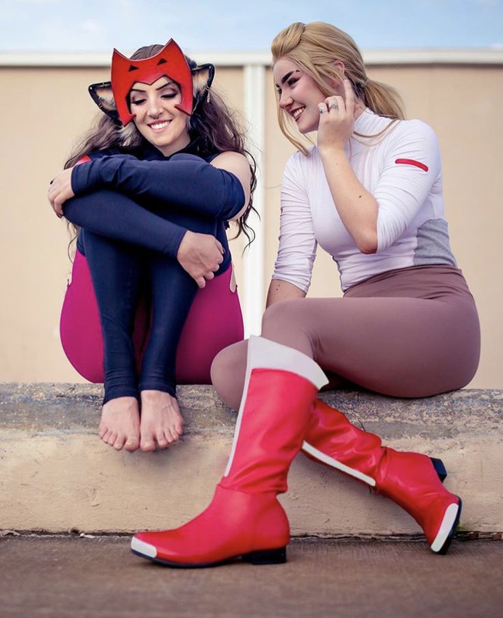 two women dressed in costumes sitting on the ground