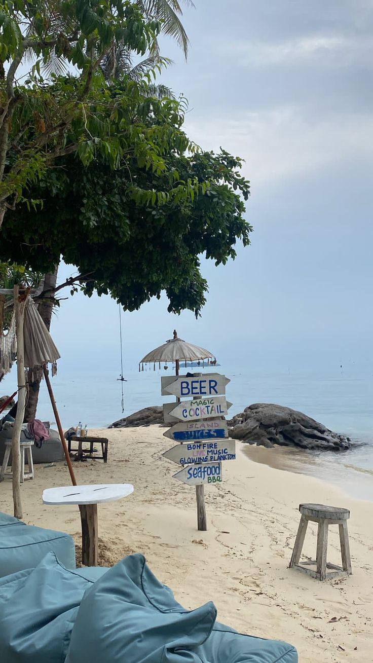 there is a sign on the beach that says beer and umbrellas next to it