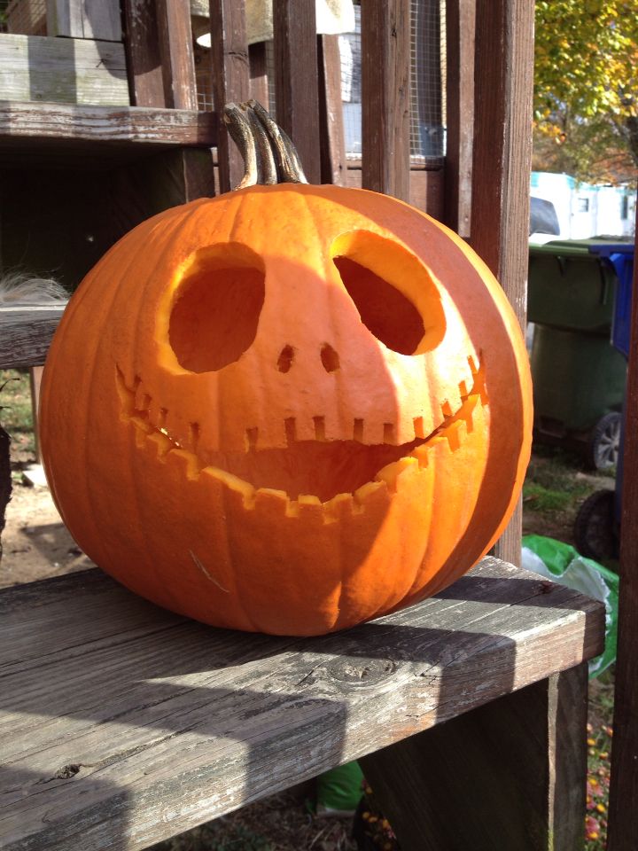 a carved pumpkin sitting on top of a wooden bench