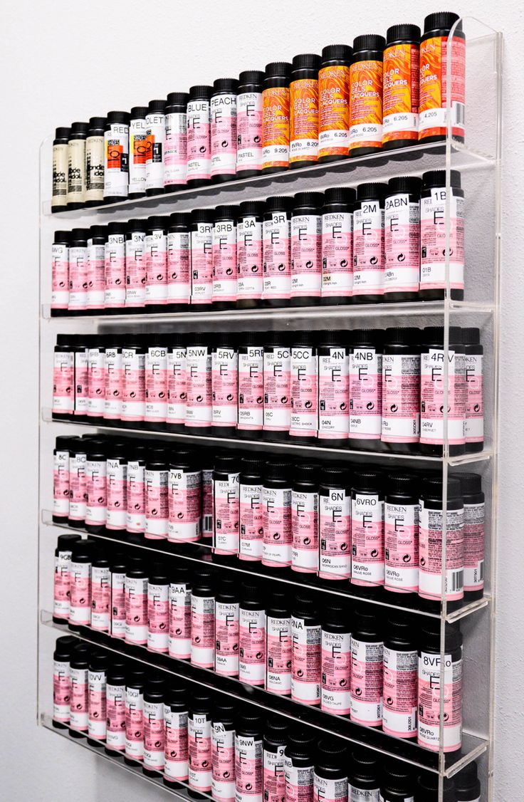 Acrylic wall hanging shelf with hair color toner bottles organized in a unique and practical manner. Shades Eq Shelf, Salon Suite Shelving, Redken Shades Organization, Redken Shades Storage Ideas, Salon Product Storage, Hair Color Organizer, Color Station Hair Salon, Hair Color Storage Ideas Small Spaces, Hair Salon Color Room Ideas