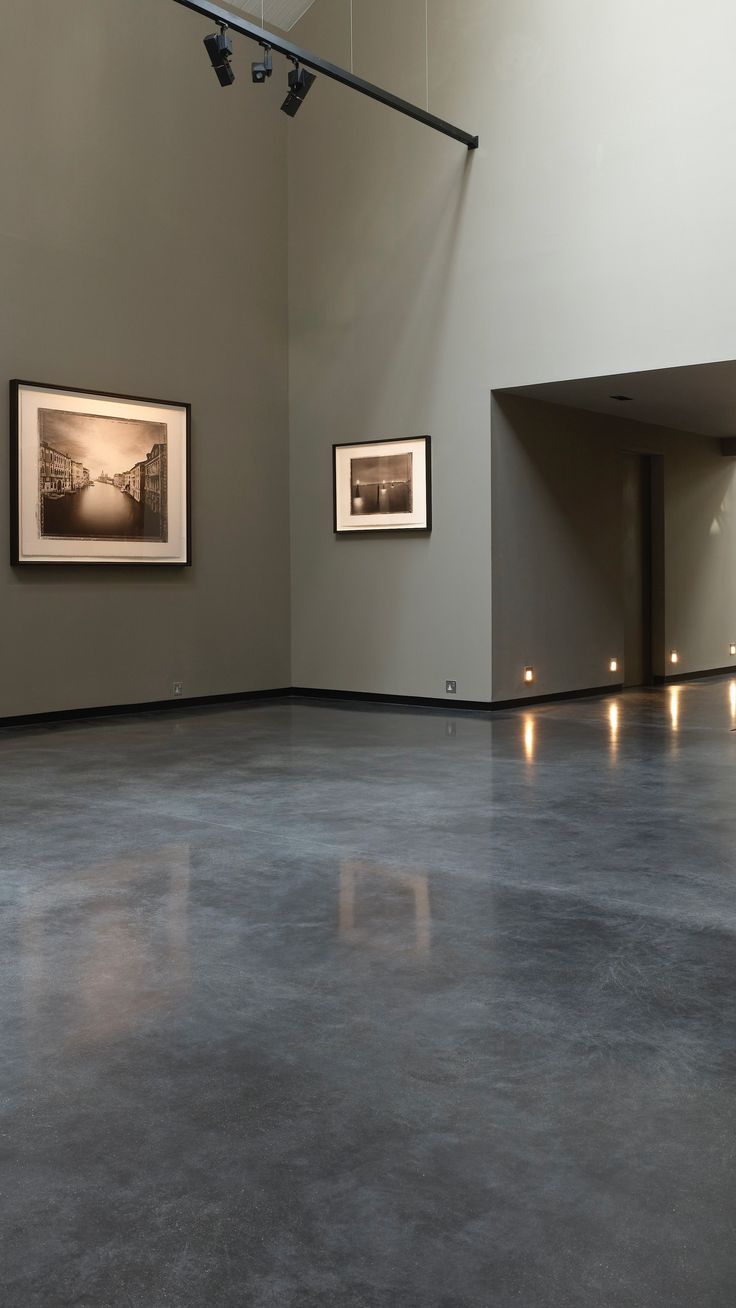 an empty room with two framed pictures on the wall and lights hanging from the ceiling