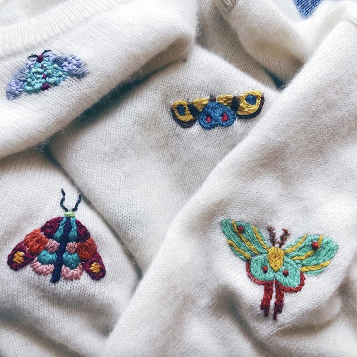 several embroidered sweaters are laying on top of each other