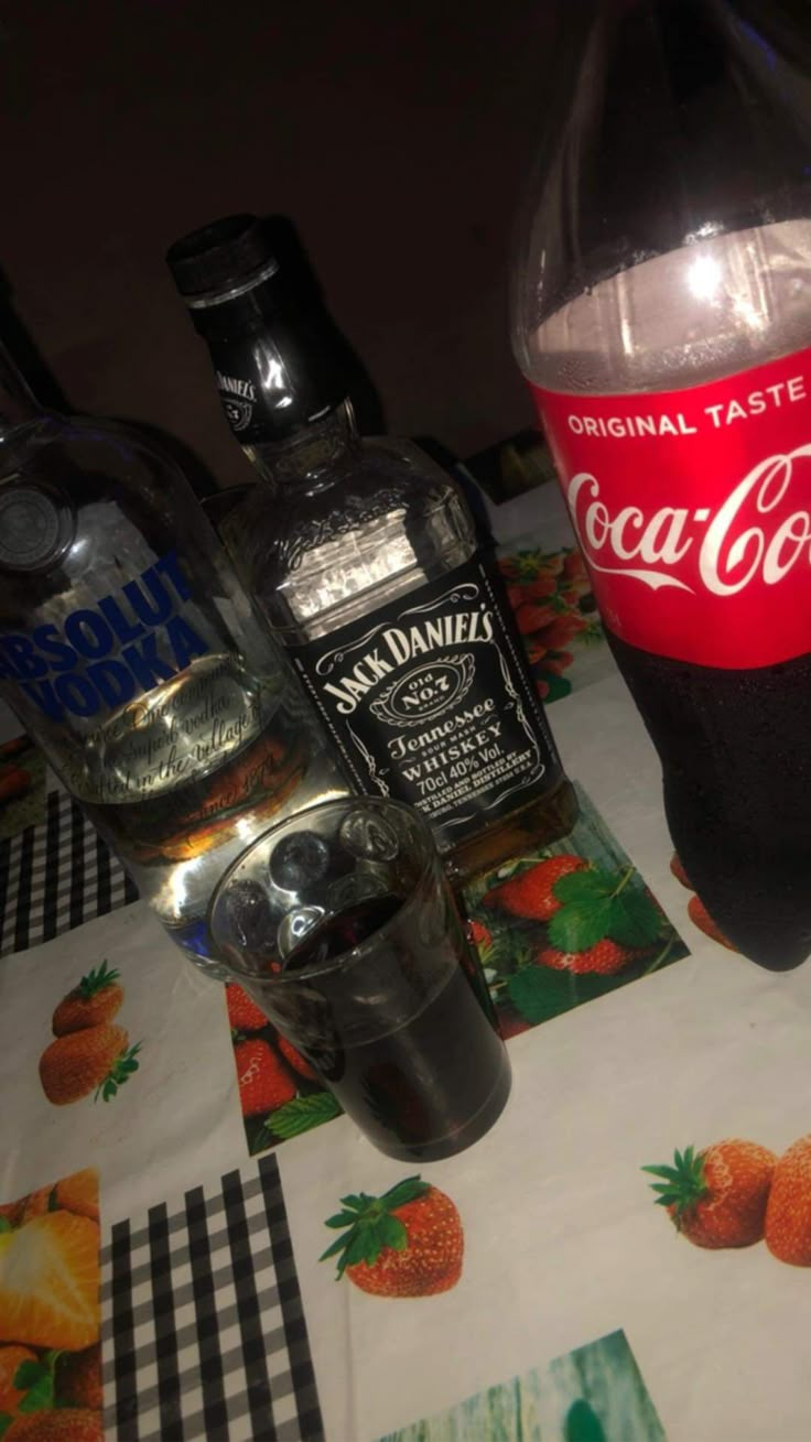 there is a bottle of coca - cola next to two empty glasses on the table