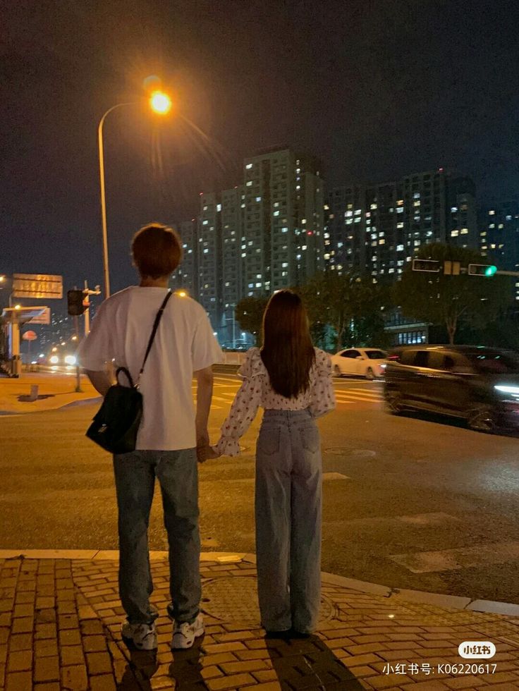 two people standing on the sidewalk at night