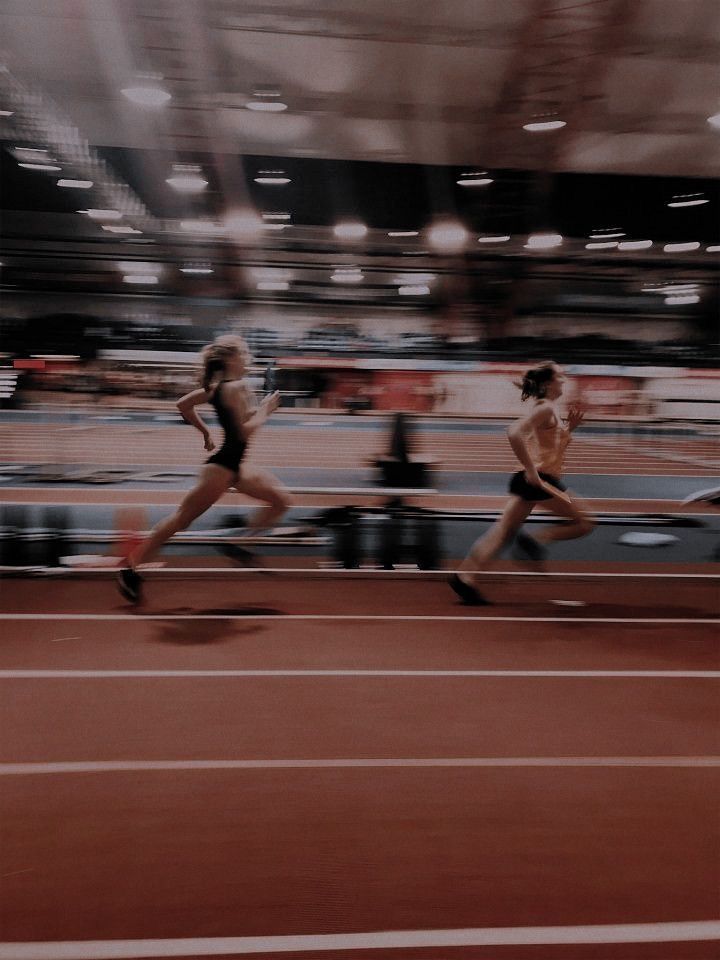 two women running on a track in a stadium