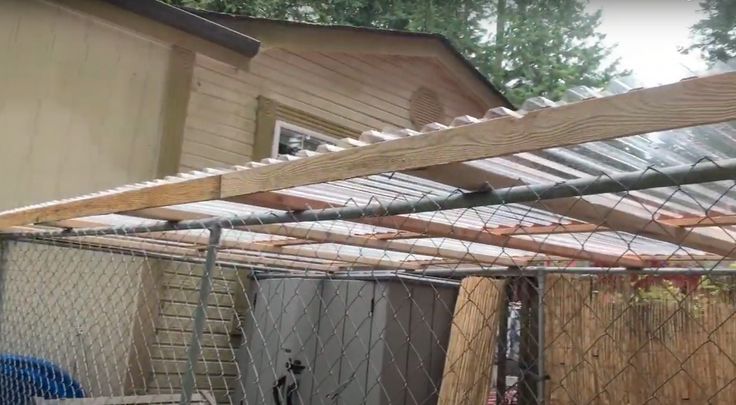 a fenced in area with wooden posts and fencing around it, next to a house