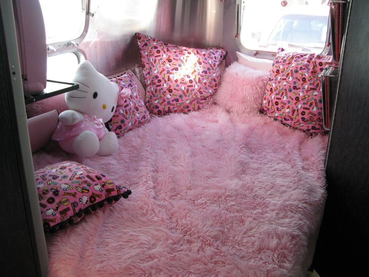 the interior of a camper with pink carpet and teddy bear on it's bed