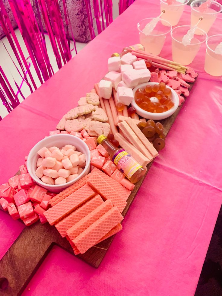 a pink table topped with lots of food and drinks