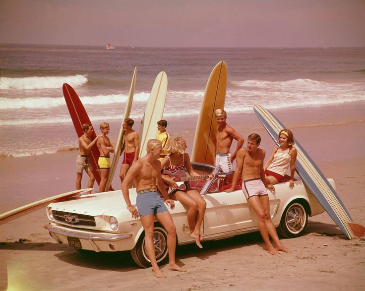 a group of people sitting on top of a car with surfboards