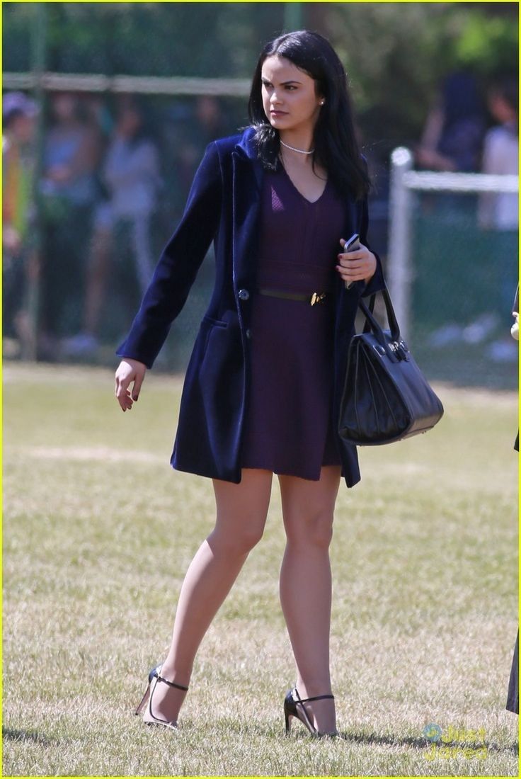 a woman in a purple dress is walking through the grass with her hand on her hip