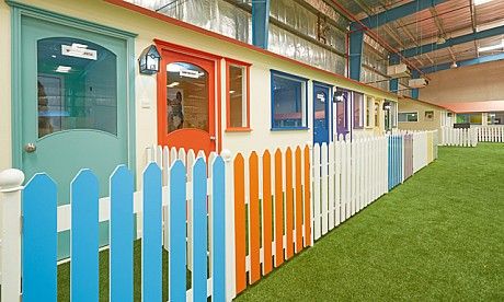 an indoor play area with fake grass and colorful doors on the side of the building