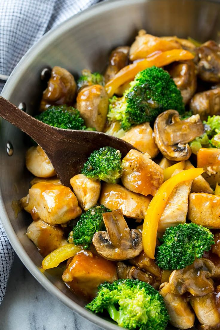 broccoli and mushrooms stir fry in a pan with a wooden spoon