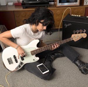 a person sitting on the floor with a guitar and amp in front of them,