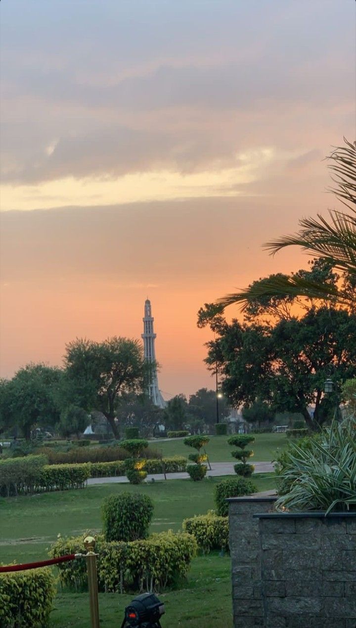 the sun is setting over a park with trees and bushes