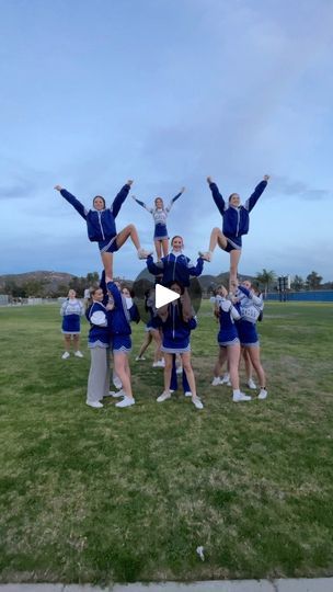 a group of cheerleaders standing on top of each other in front of a field