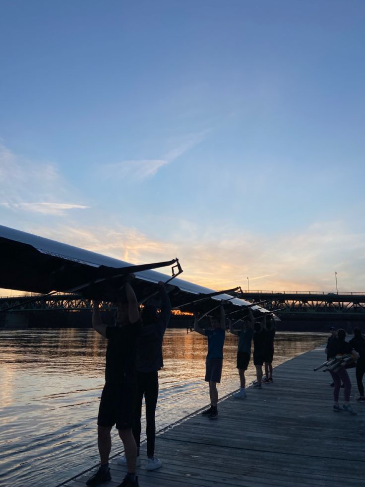 several people standing on a dock with a small plane in the air above them and water below