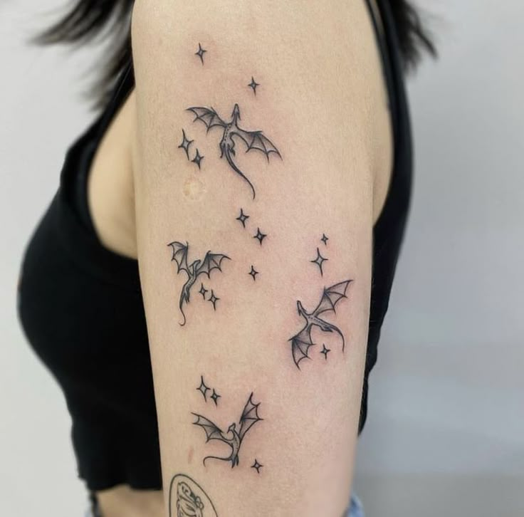 a woman with a tattoo on her arm that has stars flying in the sky above it