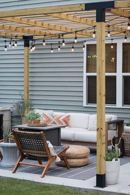 an outdoor living area with patio furniture and string lights on the pergolated roof