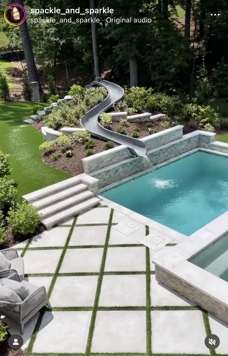 a backyard with a pool and slide in the back yard, surrounded by grass lawning