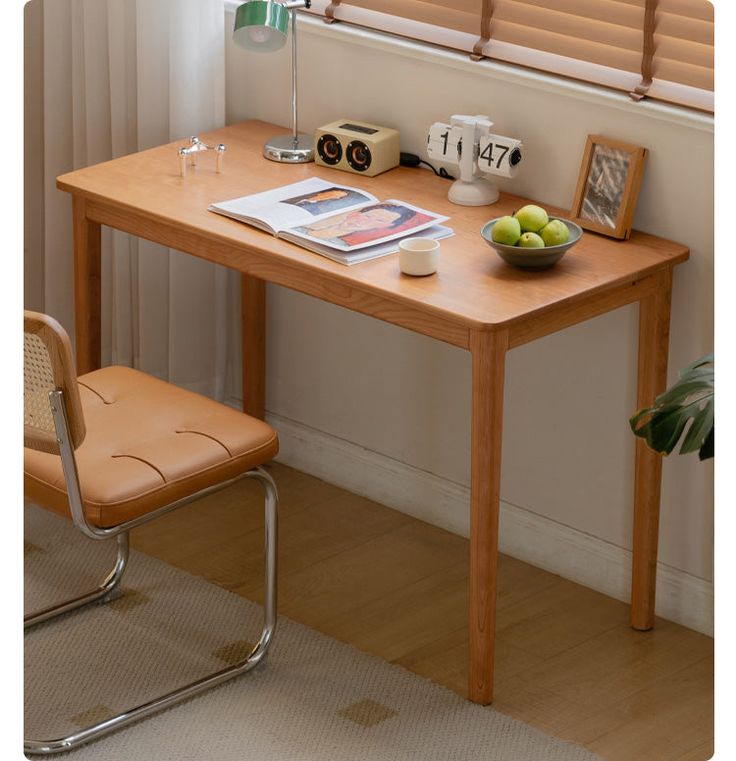 a wooden table with a bowl of fruit on top of it next to a window