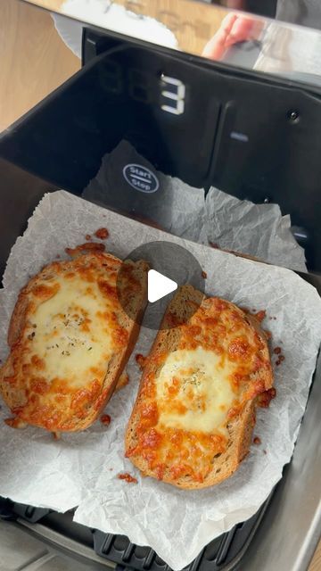 two pieces of bread sitting on top of a pan filled with cheese covered pizzas