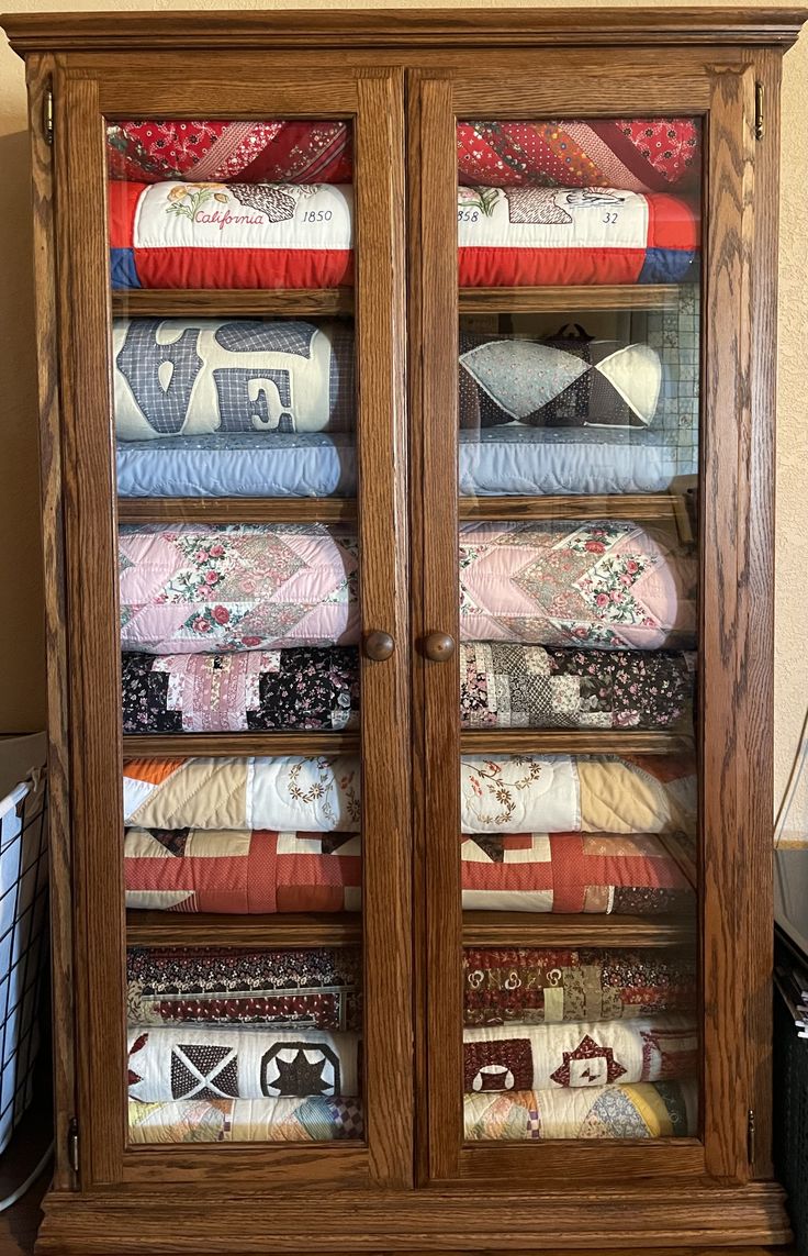 a wooden cabinet filled with lots of quilts