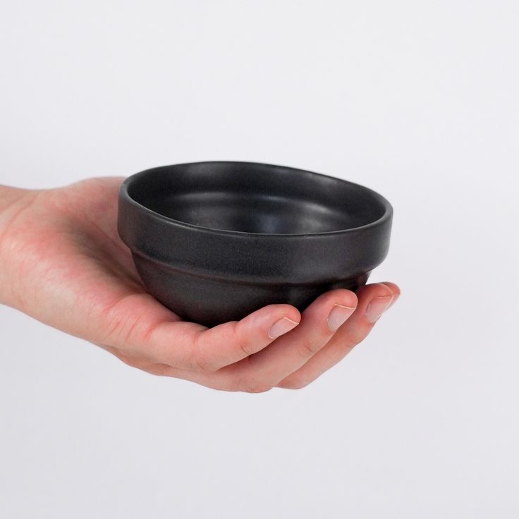 a person holding a black bowl in their hand