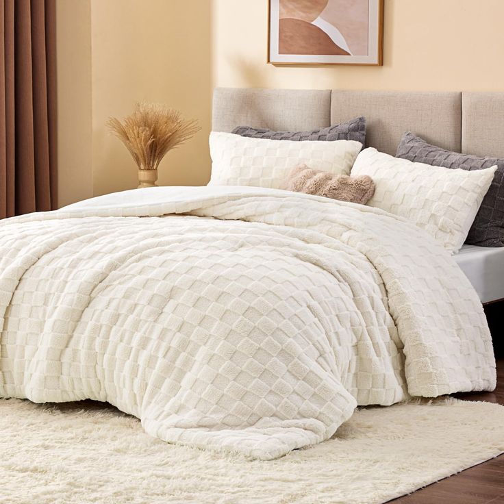 a bed with a white comforter and pillows