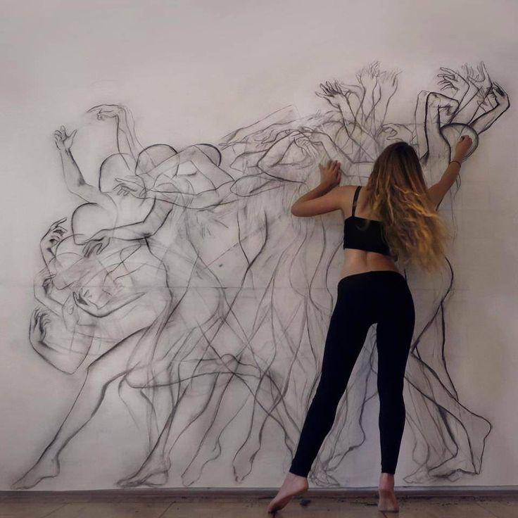 a woman standing in front of a drawing on the wall with her hands behind her head