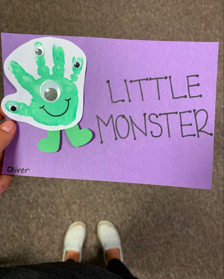 a person holding up a handprinted sign with the words little monster on it