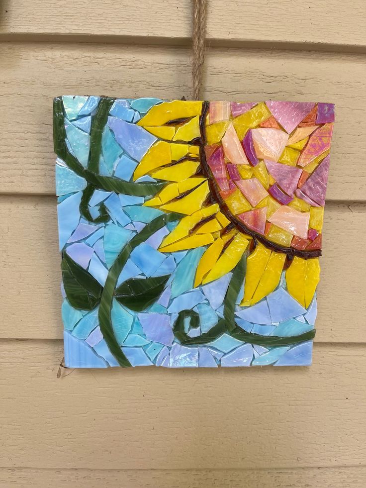 a sunflower made out of stained glass hanging on a house's front door