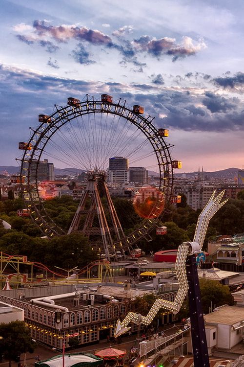 an aerial view of a ferris wheel and other amusement park rides at dusk in the city