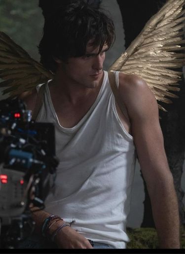 a man with wings on his back sitting in front of a camera