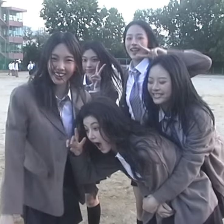 a group of young women standing next to each other on top of a dirt field