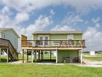 two houses on stilts in the middle of a grassy area with stairs leading up to them