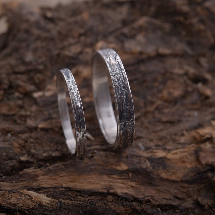 two silver rings sitting on top of a rock