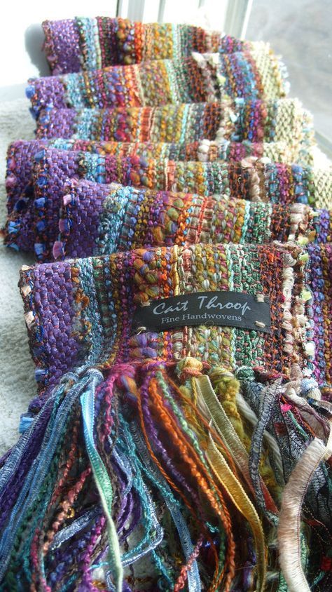 a pile of colorful scarves sitting on top of a white table next to a window