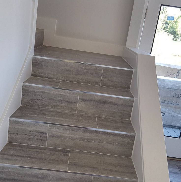 the stairs are made of wood and have gray tile on each side, along with white walls