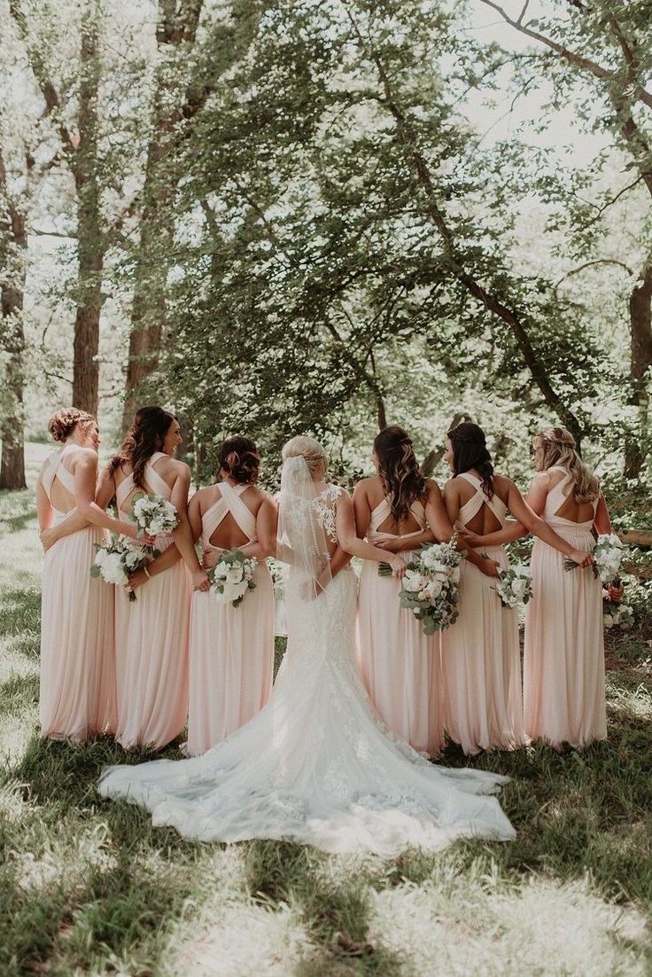 a group of bridesmaids standing together in the woods with their backs to each other